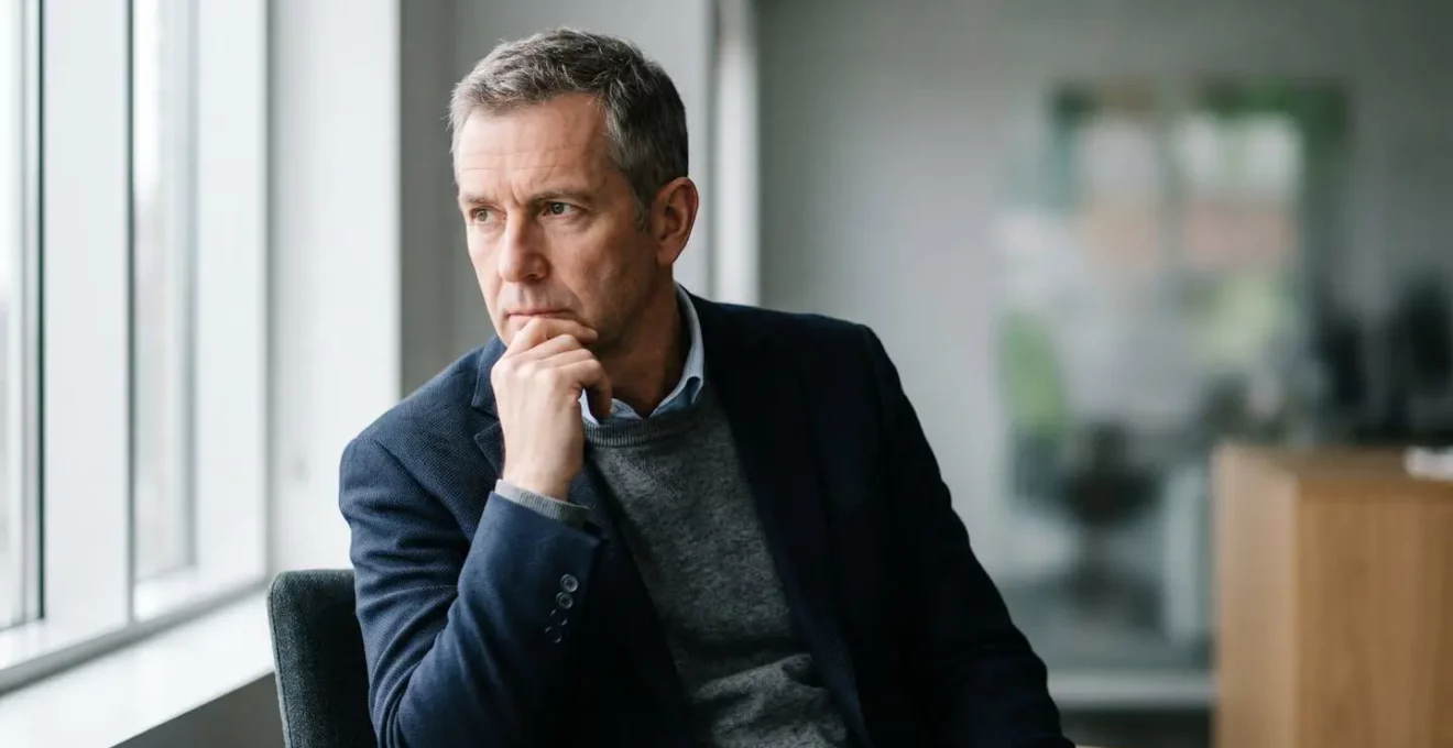 Chef d'entreprise en moment de réflexion face à des décisions financières stratégiques
